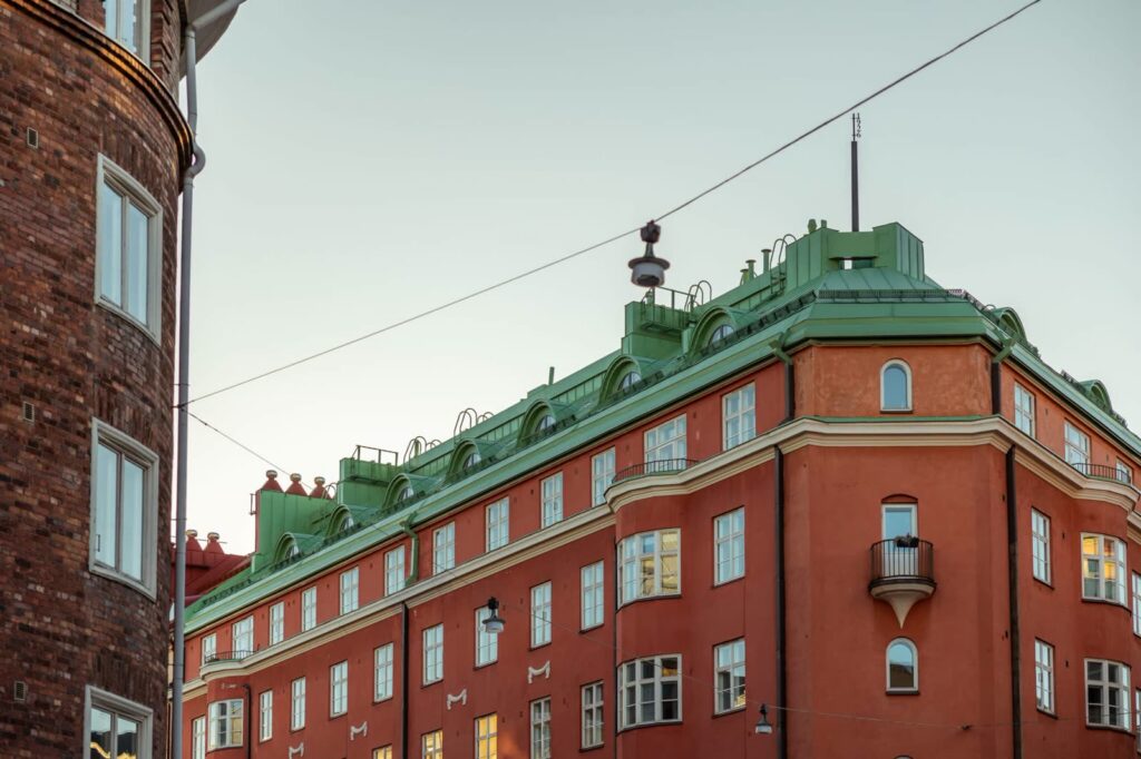 Bygård i mursten med grønt kobbertak, sett fra gatenivå