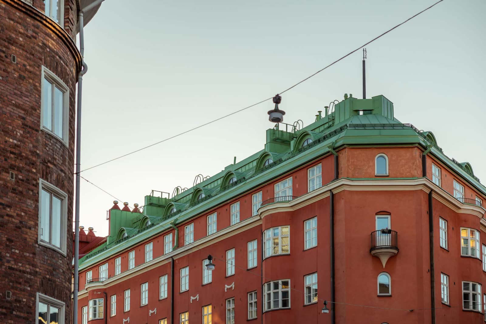 Bygård i mursten med grønt kobbertak, sett fra gatenivå