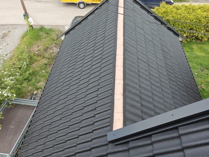 dark metal or stone-coated steel tiled roof under construction or repair