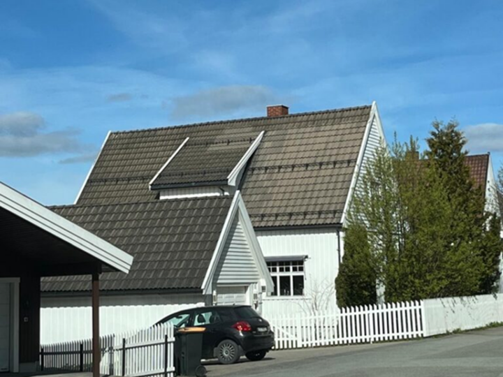 Tak av rødbrun teglstein med synlig vekst av mose og lav langs valm- og gradrenner.